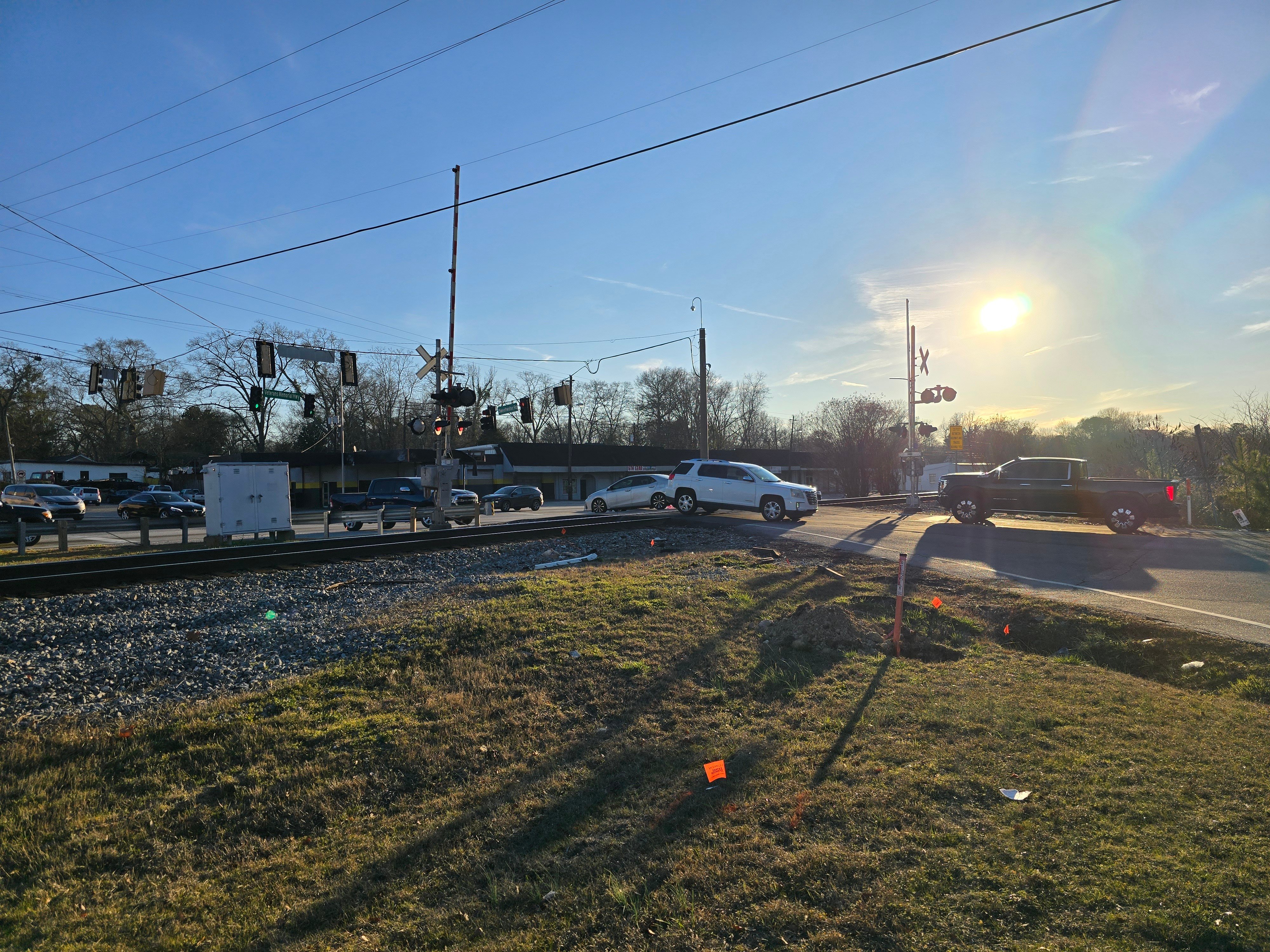 image shows vehicles crossing a railroad track at a grade crossing during late afternoon.